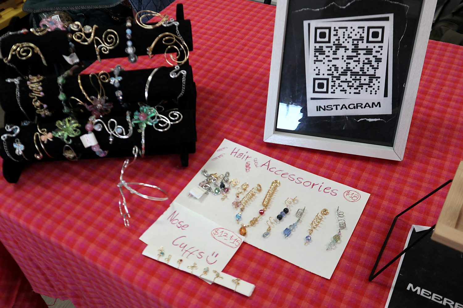 Hand-lettered hair accessories sign with wire hair coils and charms on a table