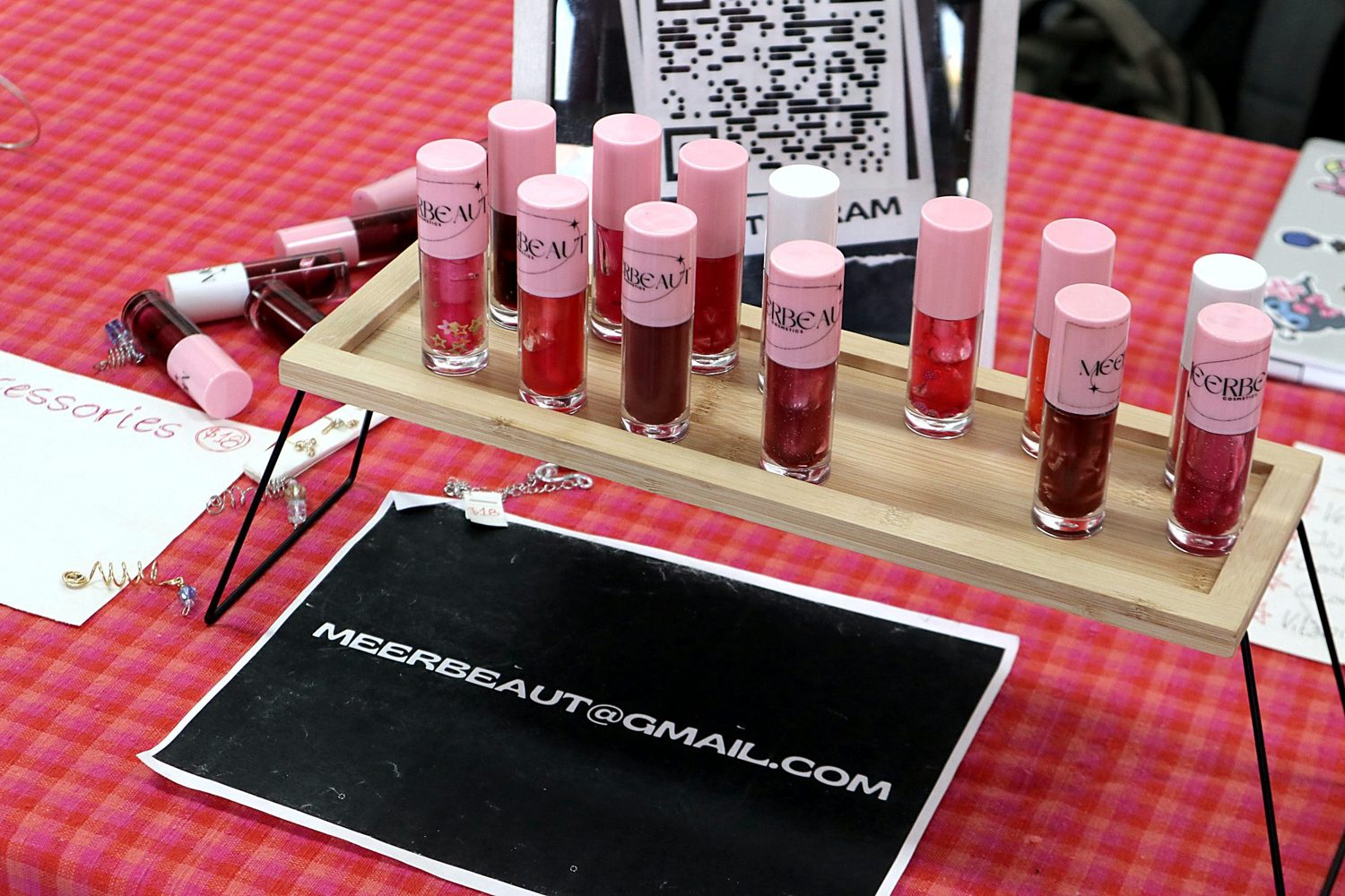 A row of MEERBEAUT glosses on a bamboo stand at our market table